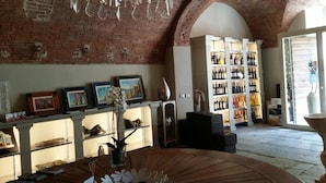 A spacious room with a brick wall, a chandelier, a wine rack, and a large window. - SestoSenso Suites (Campiglia Marittima)