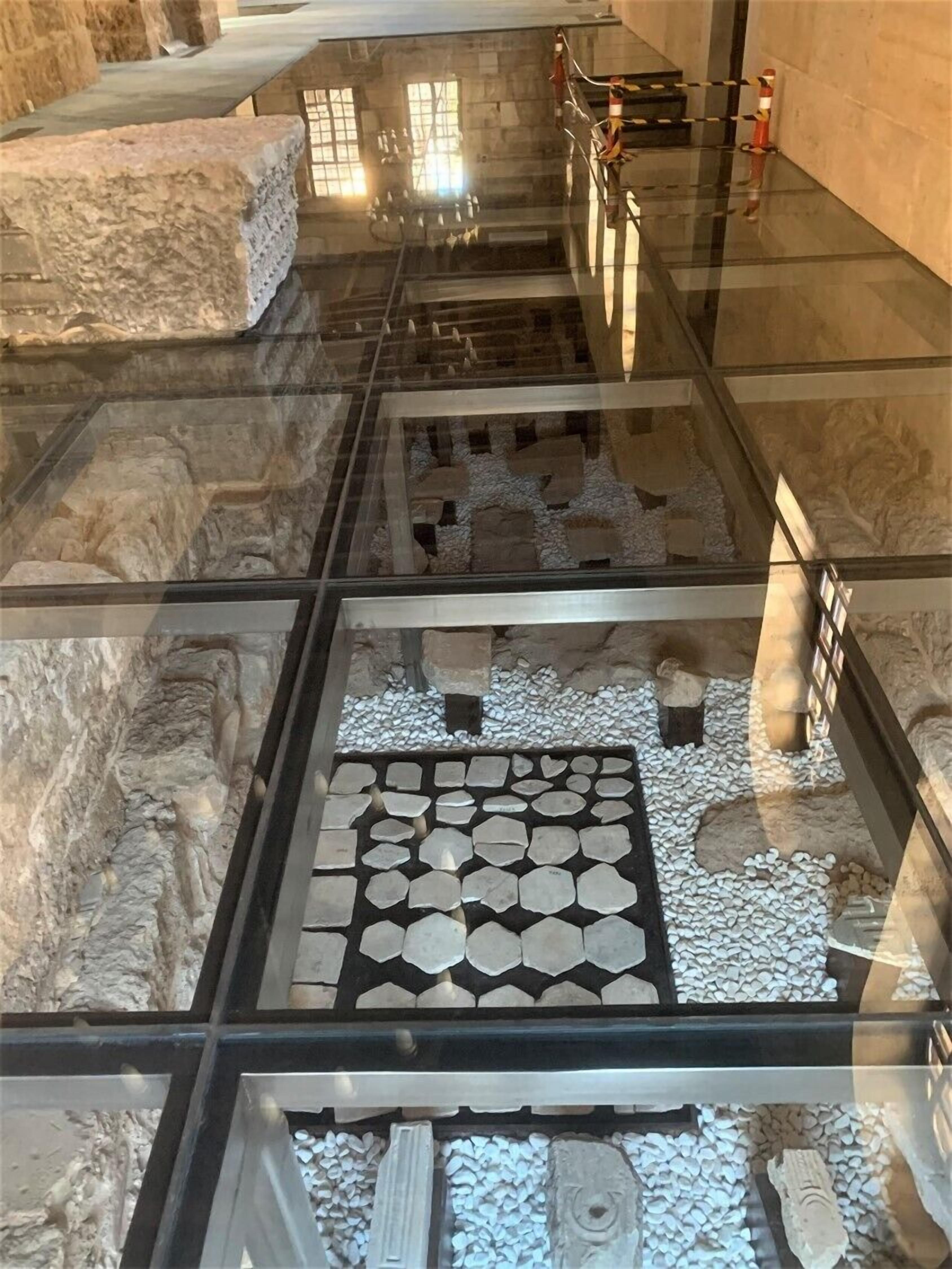 An archaeological exhibit with stone artifacts and a tiled floor.