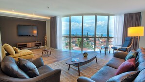 A modern living room with a large window, a flat-screen TV, and a sofa. - Arkk Homes (Antalya)