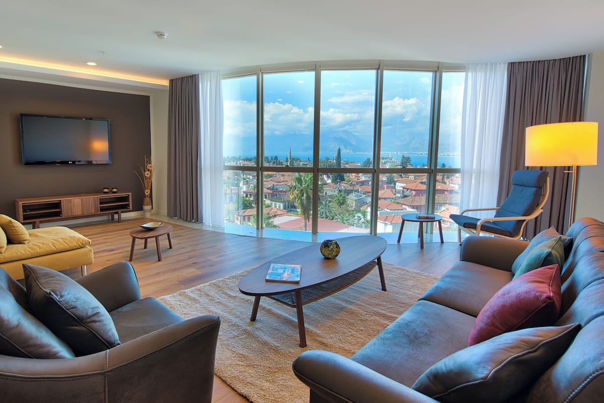 A modern living room with a large window, a flat-screen TV, and a sofa.