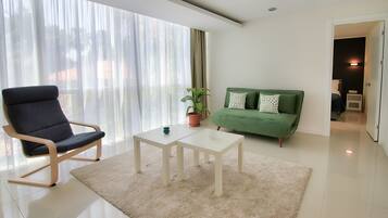 Ein modernes Wohnzimmer mit großem Fenster, einem grünen Sofa, einem weißen Couchtisch und einem blauen Sessel.