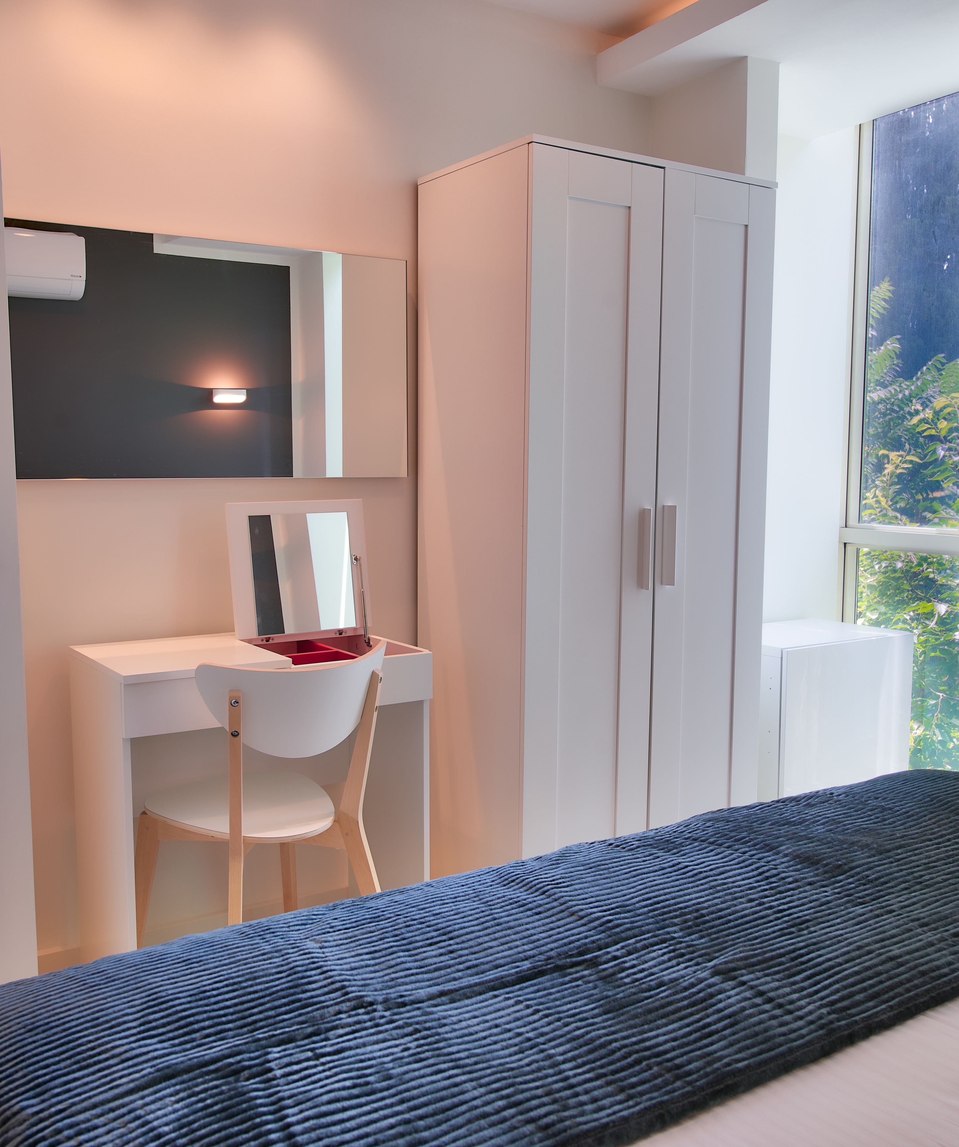 Une chambre moderne équipée d’un bureau, d’une chaise, d’une armoire et d’une grande fenêtre.