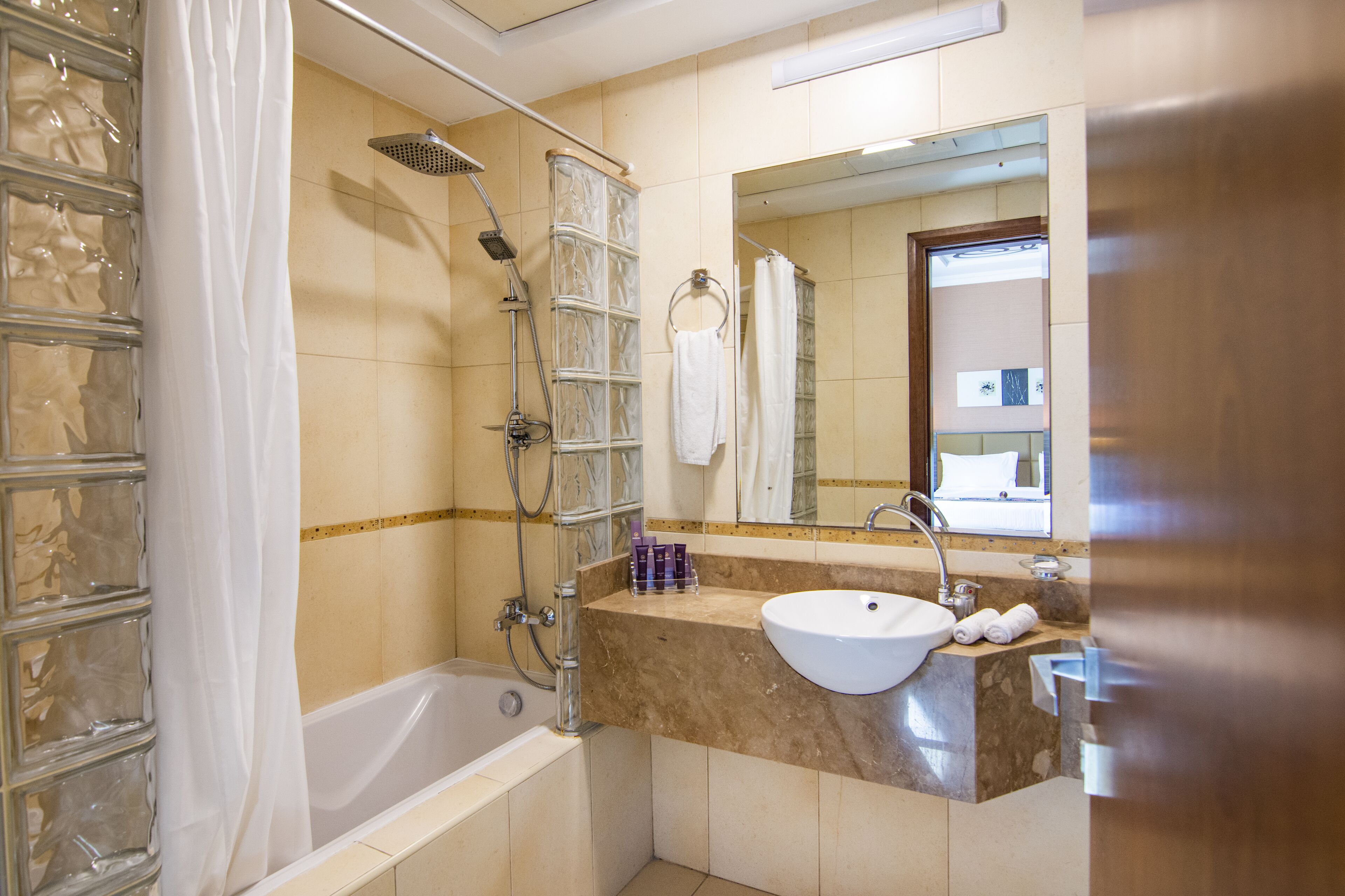 Un baño con bañera, ducha, lavamanos y espejo.
