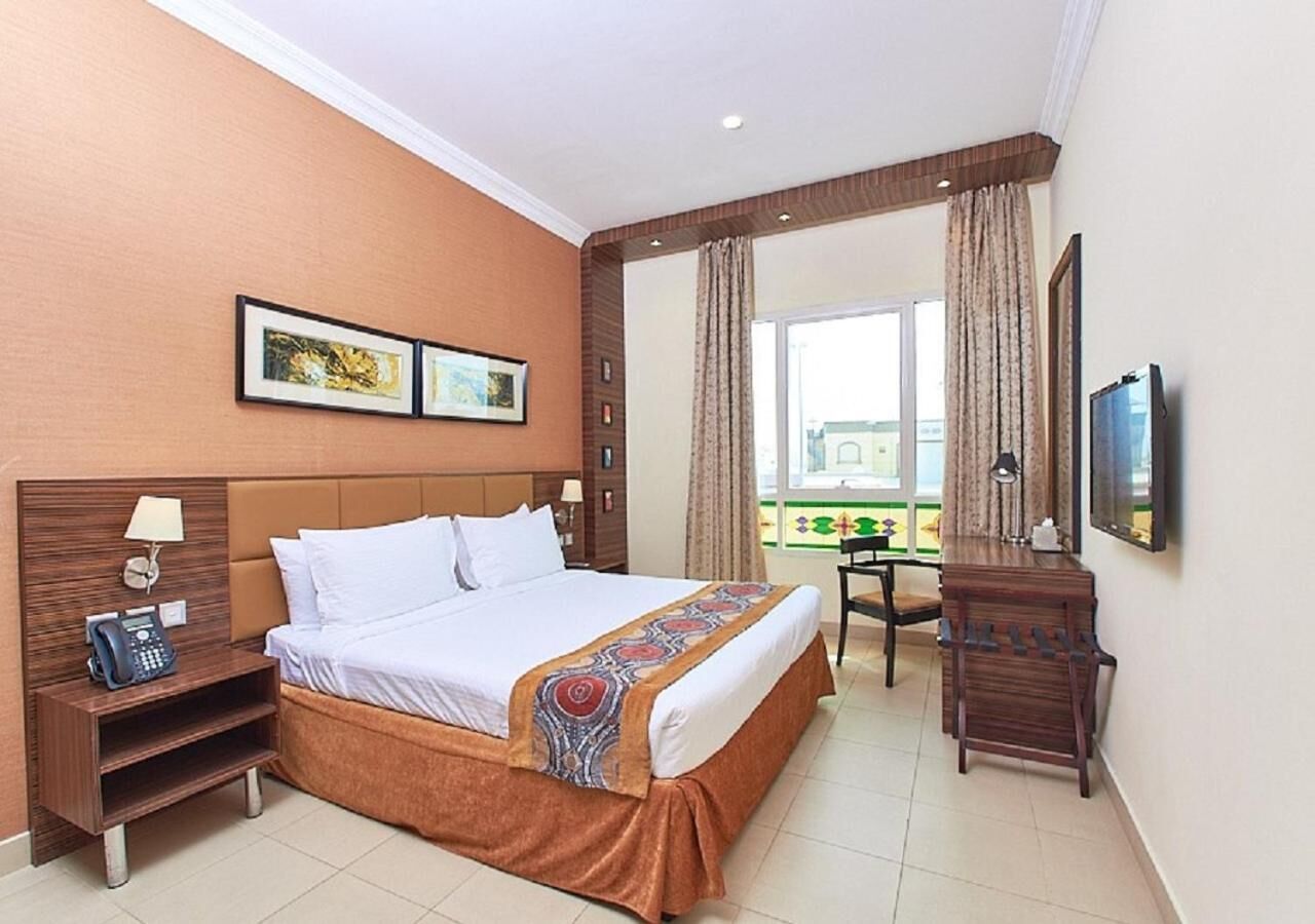 Une chambre d’hôtel équipée d’un lit, d’un bureau, d’une chaise, d’un téléphone et d’une télévision.