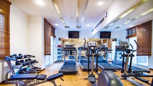 A gym with treadmills, elliptical machines, and weight benches. - Mughal Suites (Ras Al Khaimah)