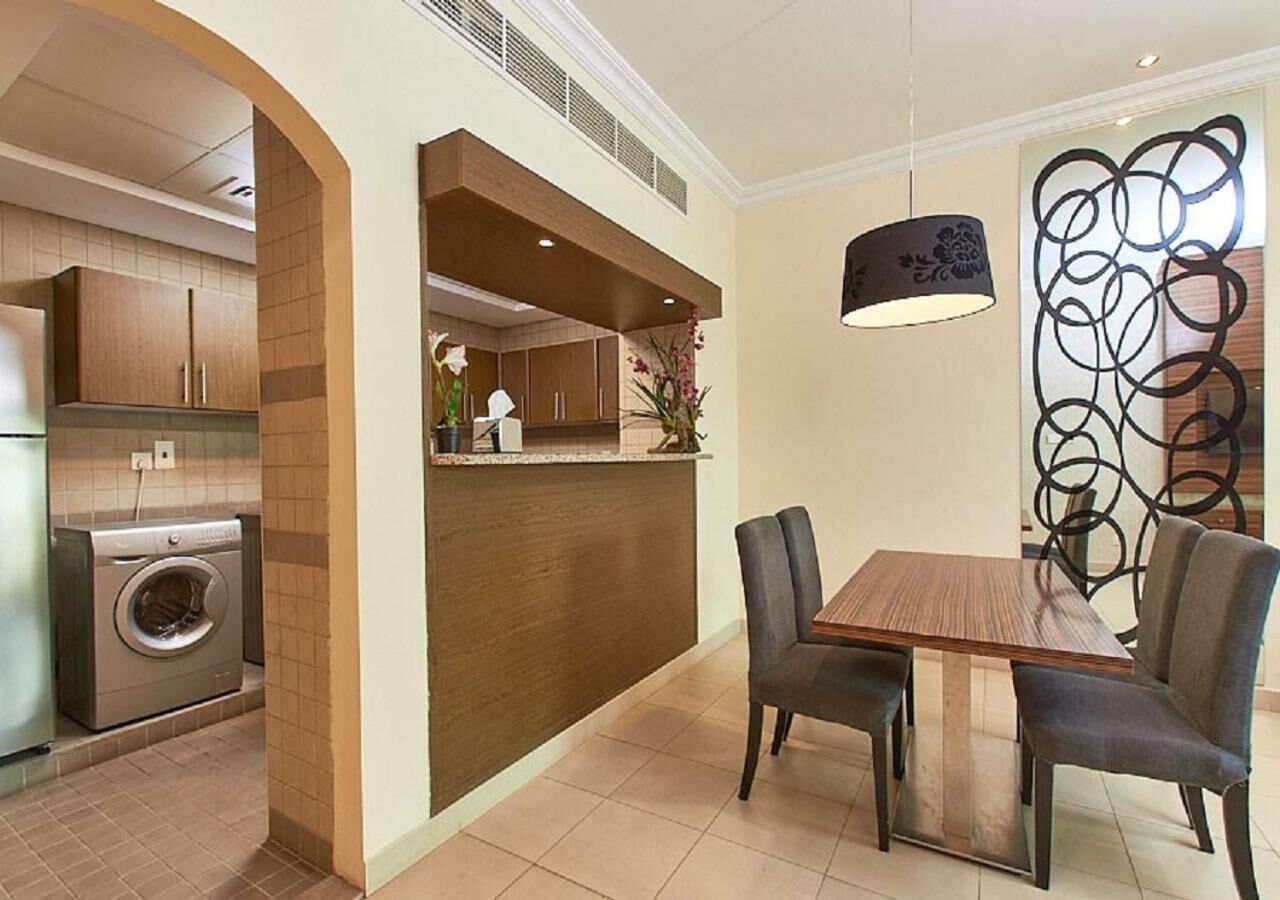 Una cocina moderna con lavadora y secadora integradas, una mesa de comedor de madera con sillas, y un adorno en la pared.