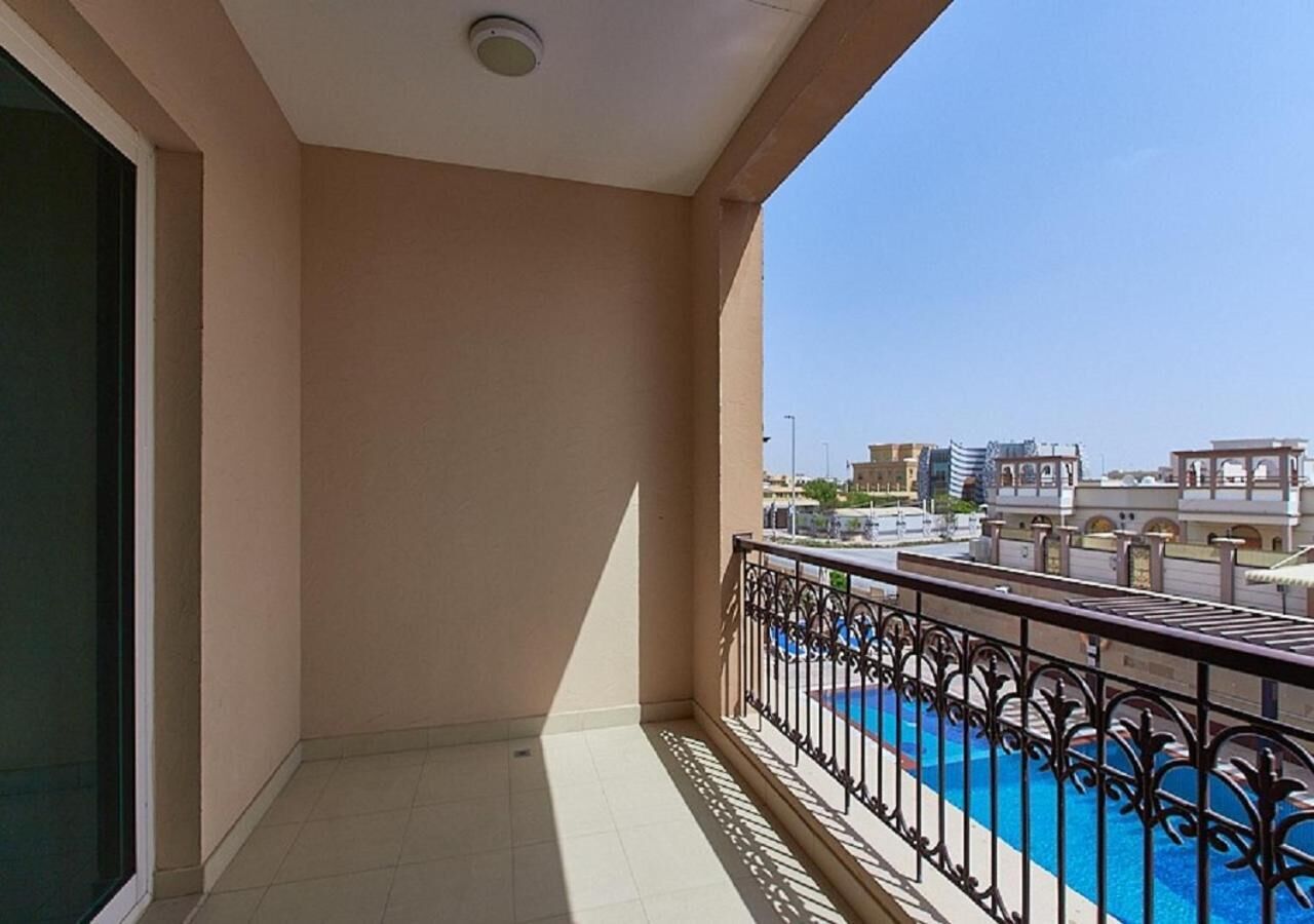 A balcony with a view of a swimming pool and surrounding buildings.