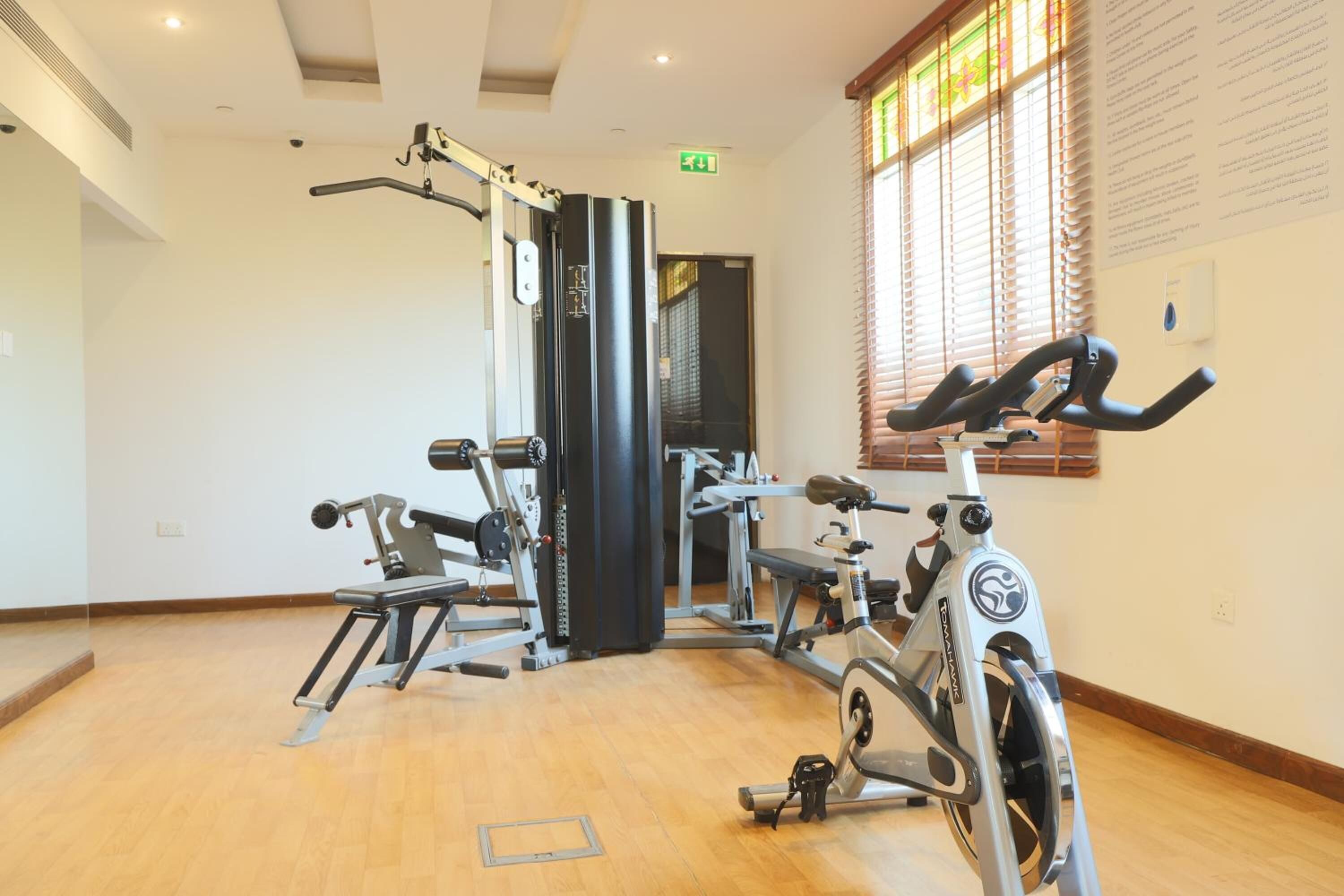 Un gimnasio con máquinas de cardio, equipo de levantamiento de pesas y un espejo grande.