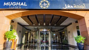 The entrance to Mughal Suites with a glass door, a red rope barrier, and potted plants on either side. - Mughal Suites (Ras Al Khaimah)