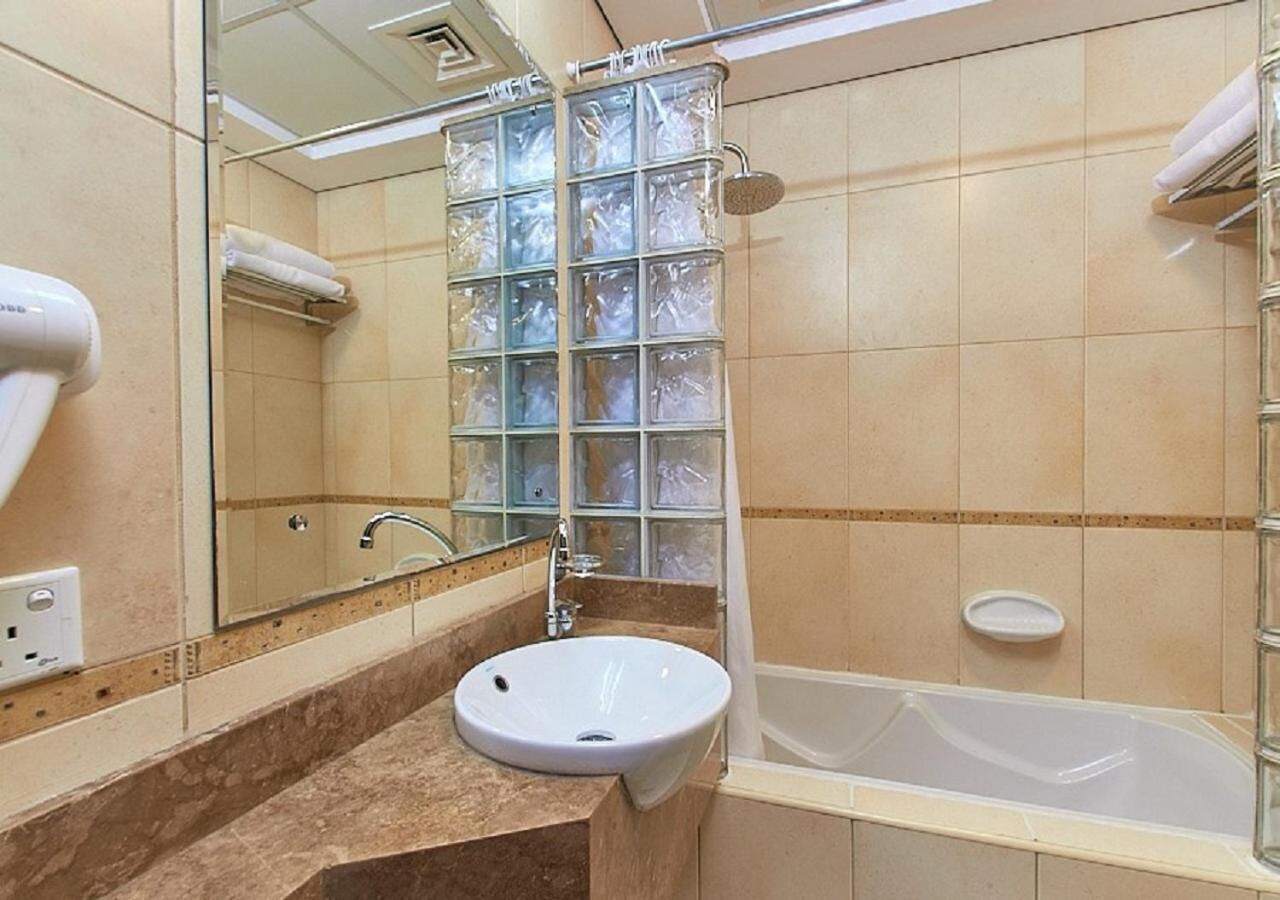 Un baño con lavamanos, espejo, ducha y cabina de ducha de vidrio.
