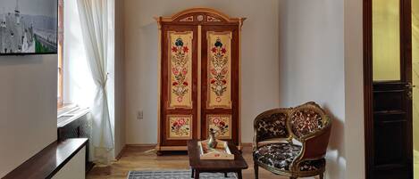 Una habitación con techo de madera, un armario grande con diseños florales, un televisor y una silla.