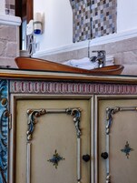 Un baño con un lavamanos decorativo, un espejo y un toallero.