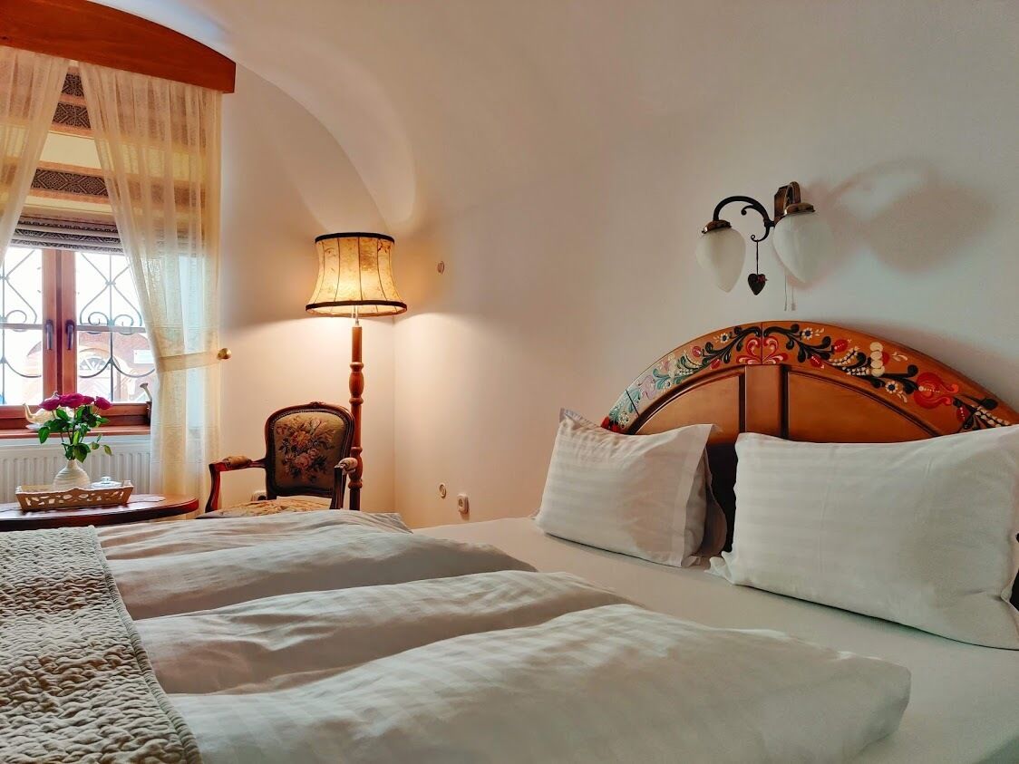 A hotel room with a large bed, a nightstand, a lamp, and a decorative headboard.