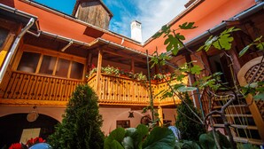 A courtyard with a wooden balcony, a chimney, and a view of the sky. - La Teo Pensiune si Pivnita (Sighisoara)