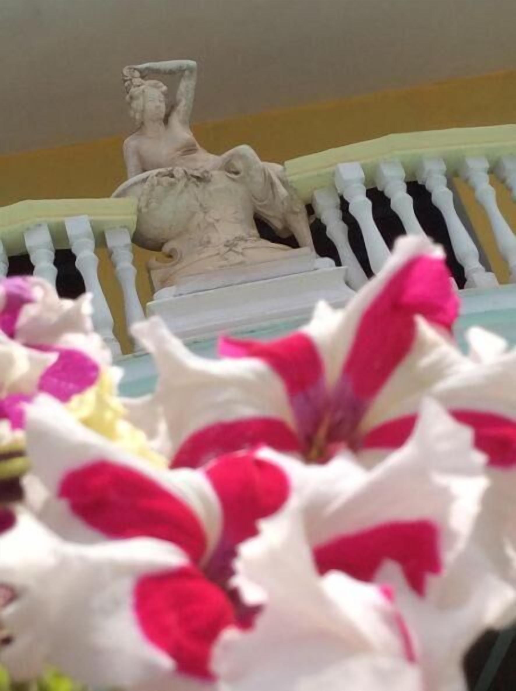 Una estatua sobre una barandilla blanca, con un muro amarillo de fondo.