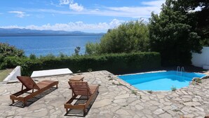 A pool with a view of the sea, surrounded by stone tiles and wooden loungers. - Hosteria Ventus Patagonia (San Carlos de Bariloche)