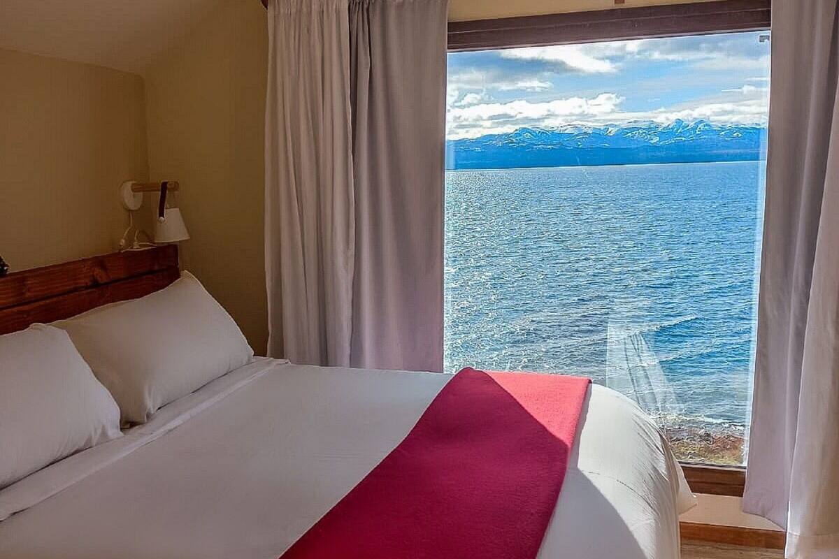 Ein Hotelzimmer mit einem großen Bett, Meerblick und einem Berg im Hintergrund.