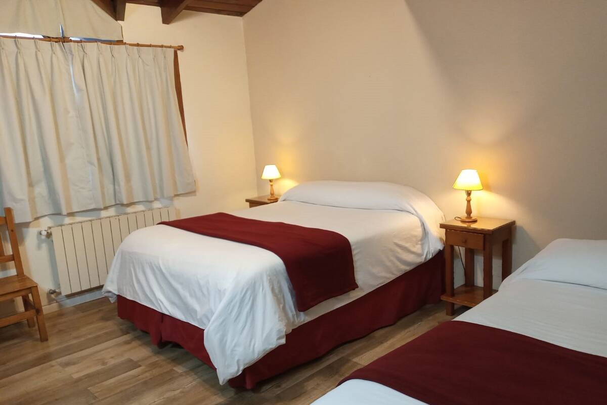 Ein Hotelzimmer mit zwei Betten, Holzböden, einem Heizkörper und zwei Nachttischlampen.