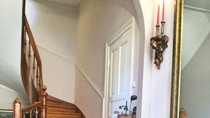 A staircase with wooden railings, a red carpet, a checkered floor, a bench with floral upholstery, and a wall-mounted mirror. - LOFTvorSYLT (Friedrichstadt)