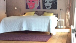 A bedroom with a bed, a nightstand, a lamp, and two posters on the wall. - LOFTvorSYLT (Friedrichstadt)