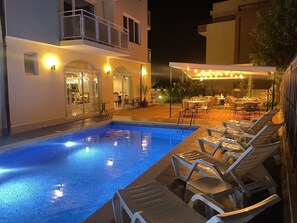 Una piscina al aire libre, sillones reclinables de piscina