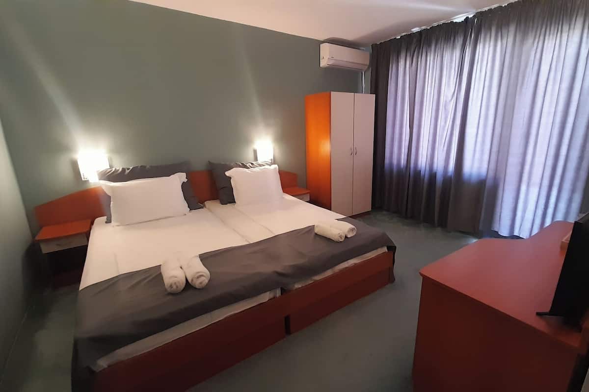 Una habitación de hotel con cama, escritorio, armario y cortina.
