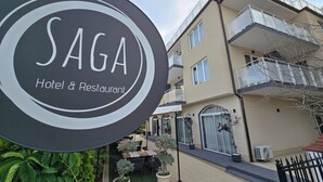 Placa de 'SAGA Hotel & Restaurant' com um edifício ao fundo.