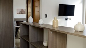 Une chambre d’hôtel moderne avec une console en bois, un téléviseur à écran plat fixé au mur et un lit doté d’une tête de lit en bois.