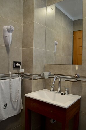A bathroom with a sink, mirror, towel rack, and hairdryer. - XV Apartamentos (La Plata)