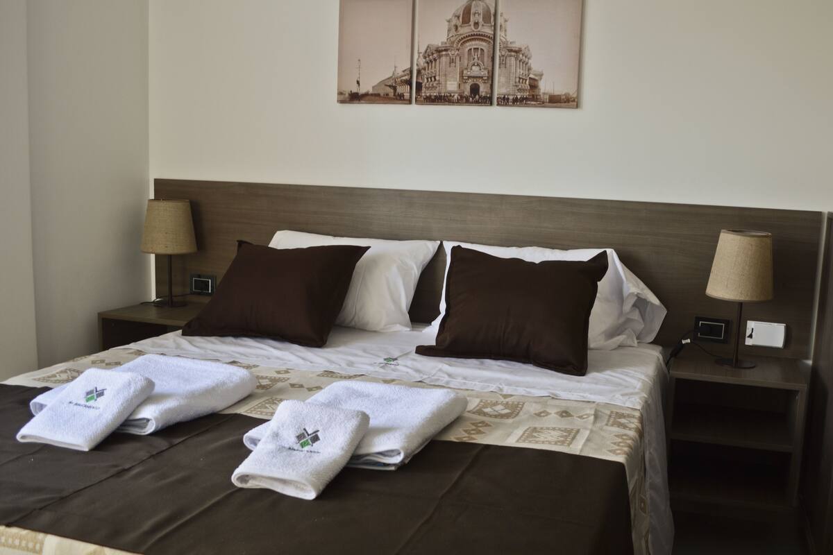 A hotel room with a large bed, two nightstands, two lamps, and a wall-mounted picture.