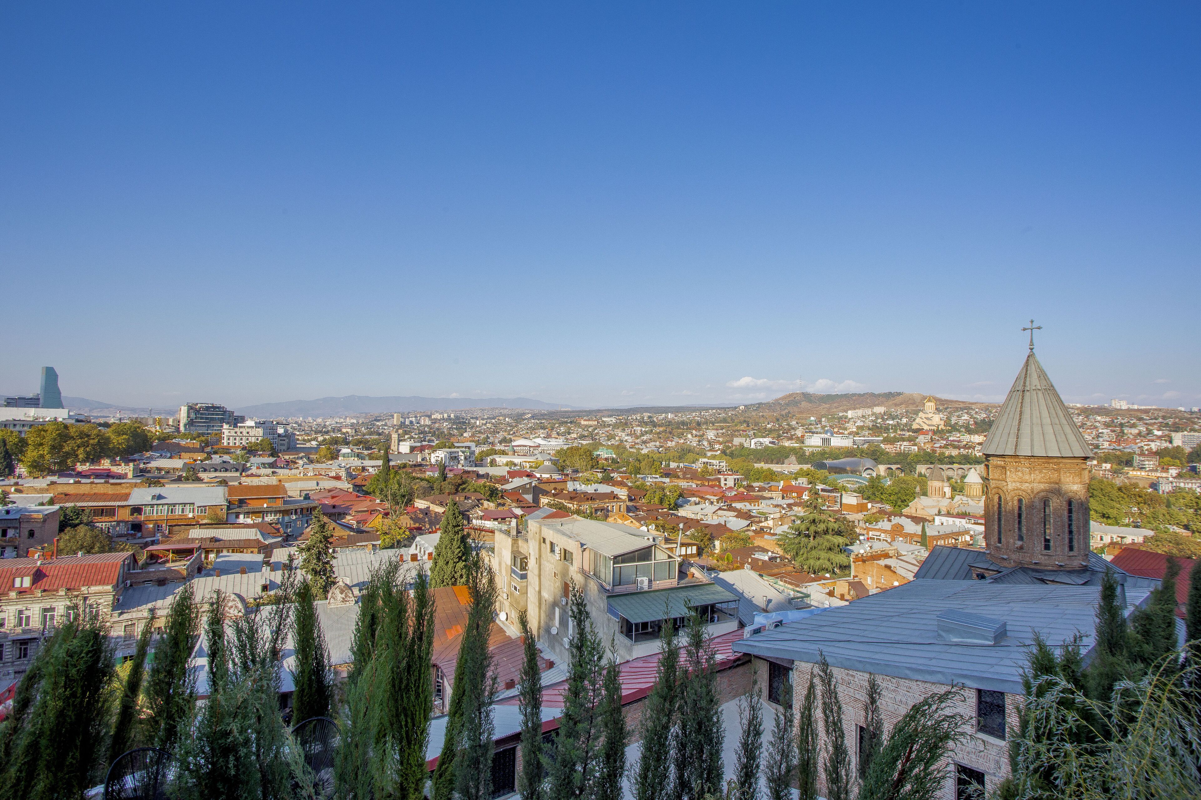 A panoramic view of a cityscape with a prominent church tower, dense residential buildings, and a mix of modern and traditional architecture.