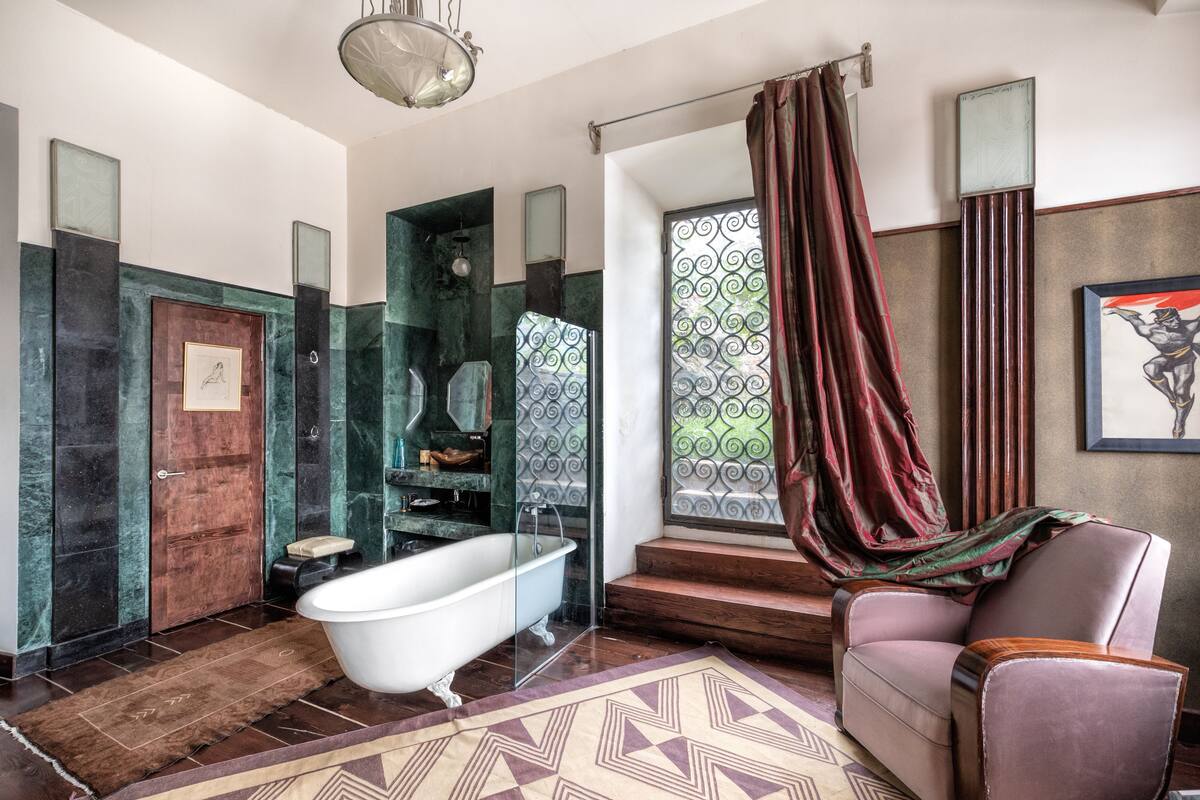 A bathroom with a freestanding bathtub, a shower with a glass door, a large window with a view, and a chair by the window.