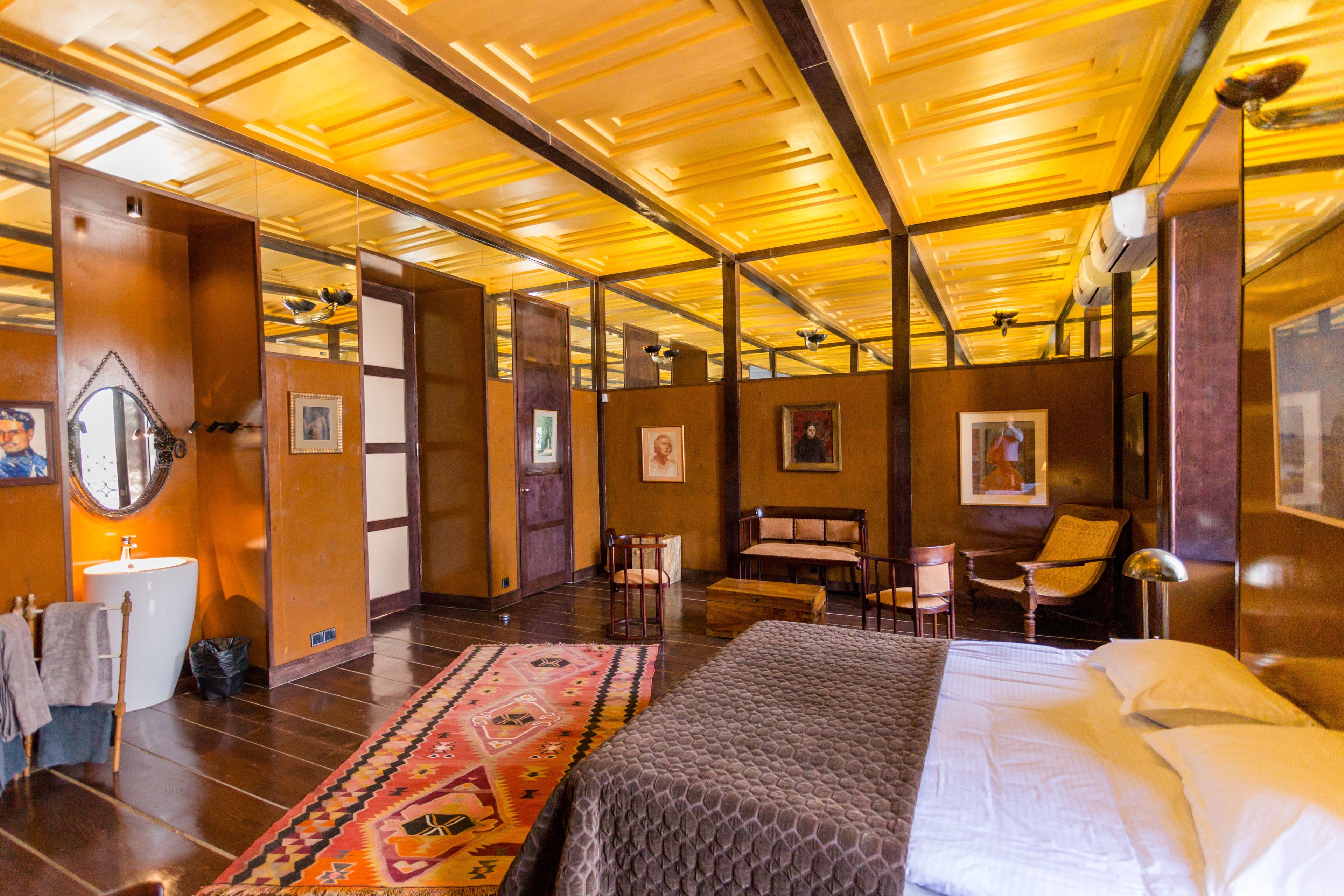 A hotel room with a large bed, a sitting area with chairs, a small table, and a mirror.