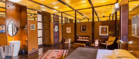 A hotel room with a large bed, a sitting area with chairs, a small table, and a mirror.