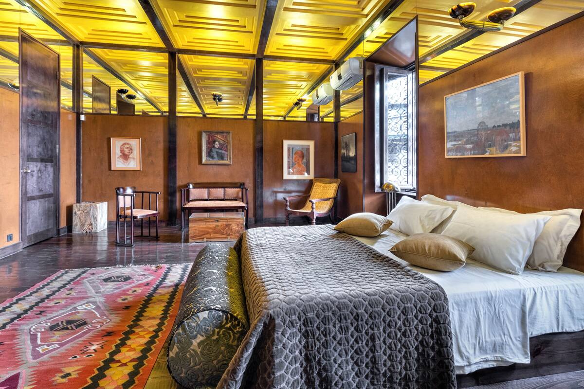 A modern bedroom with a large bed, a patterned rug, and artwork on the walls.