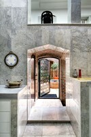 A modern bathroom with a marble floor, a sink with a decorative bowl, and a mirror with a clock.