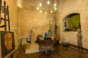 Una habitación con paredes de ladrillo, suelo de madera, una araña y varios objetos decorativos.