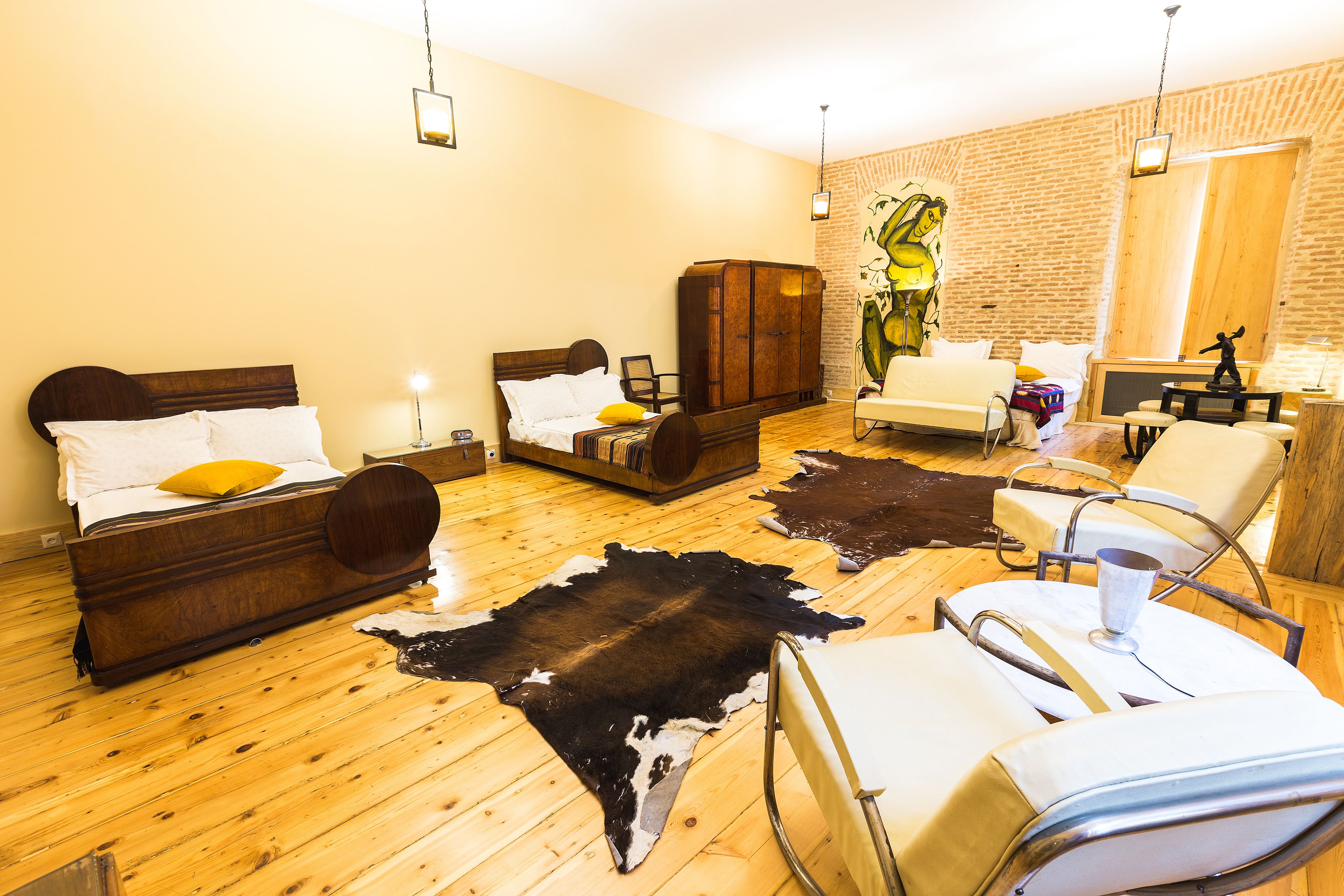 A room with a bed, a sofa, a chair, and a wooden cabinet.
