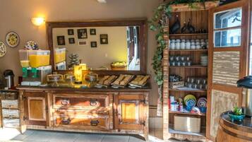 Un rincón de bar rústico con armarios de madera, una máquina de café y una variedad de tazas y vasos.