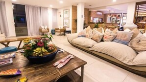 A modern living room with a sofa, a coffee table, and a potted plant. - Pousada da Prainha (Arraial do Cabo)