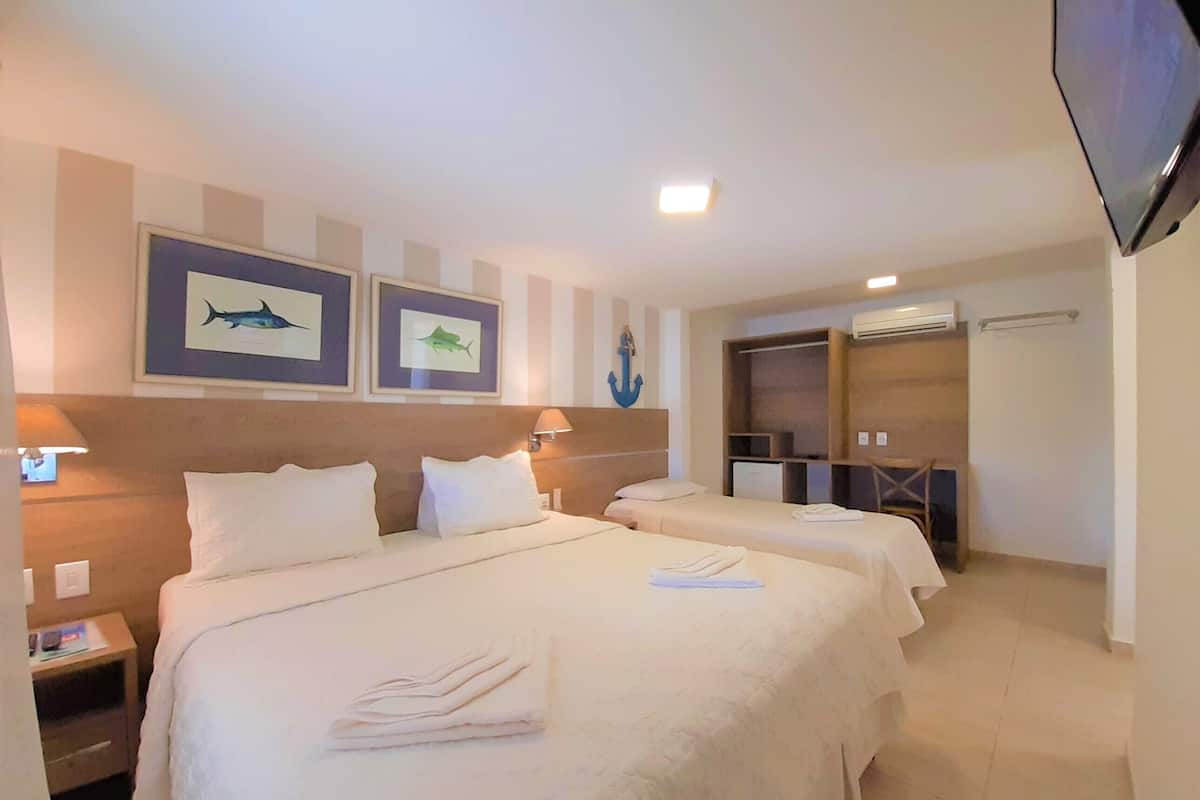 A hotel room with two beds, a desk, a chair, a TV, and a wardrobe.