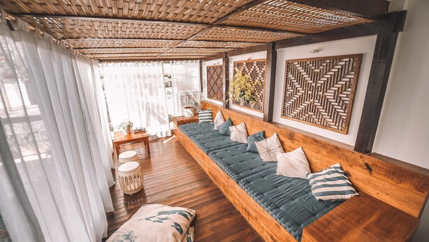 A room with a long wooden bench, a woven ceiling, and patterned wall panels. - Pousada da Prainha (Arraial do Cabo)