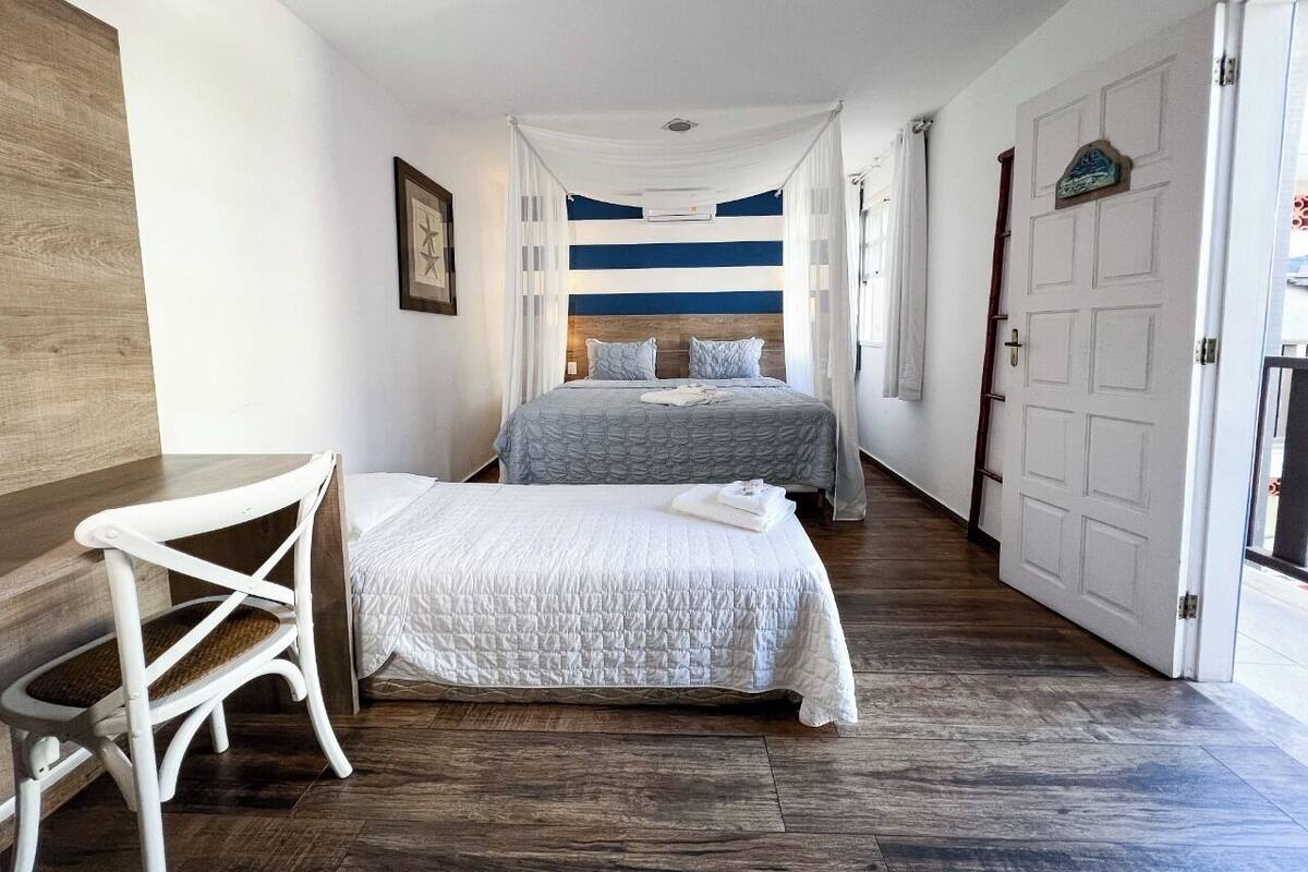 A bedroom with a large bed, a smaller bed, a chair, and a wooden table.