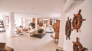 A spacious living area with a sofa set, a coffee table with decorative items, and wall-mounted ship wheels. - Pousada da Prainha (Arraial do Cabo)