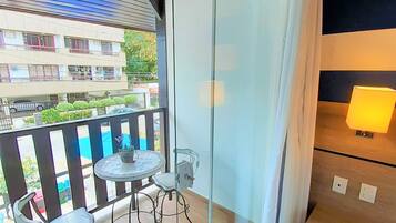 A balcony with a table and chairs, a lamp, and a view of a building.