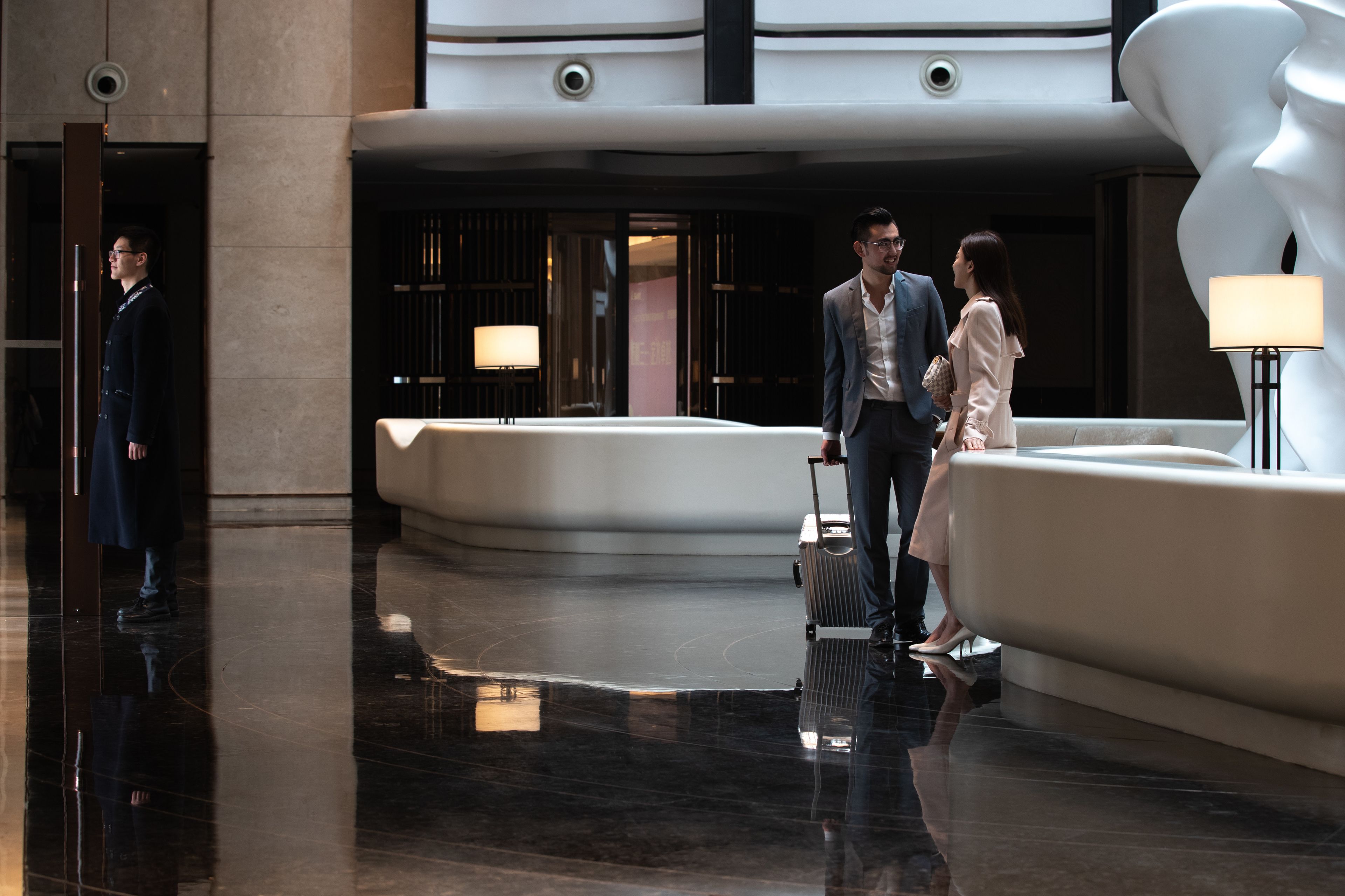 A modern lobby with a marble floor, a seating area, and a large white sculpture.