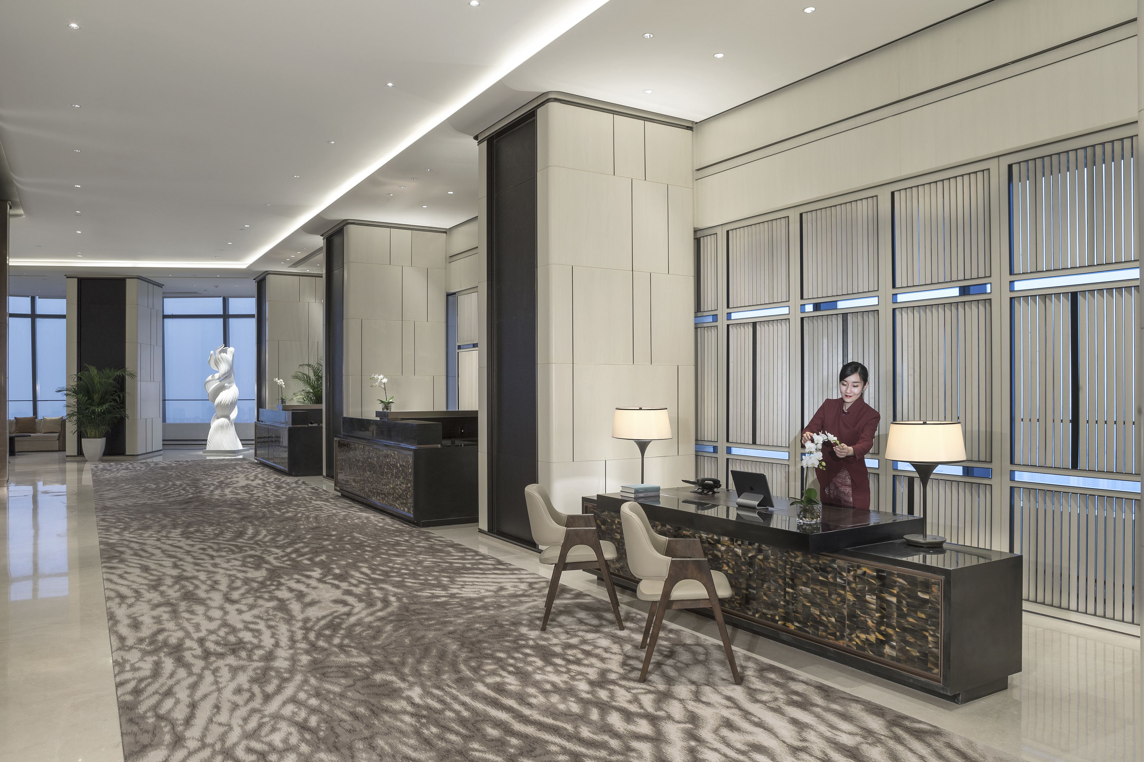 Eine moderne Hotelhalle mit Empfangstresen, Sitzgelegenheiten und Dekorationselementen.