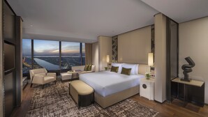 Ein modernes Hotelzimmer mit einem großen Bett, einer Sitzecke mit Blick und einer Stadtsicht durch die Fenster.