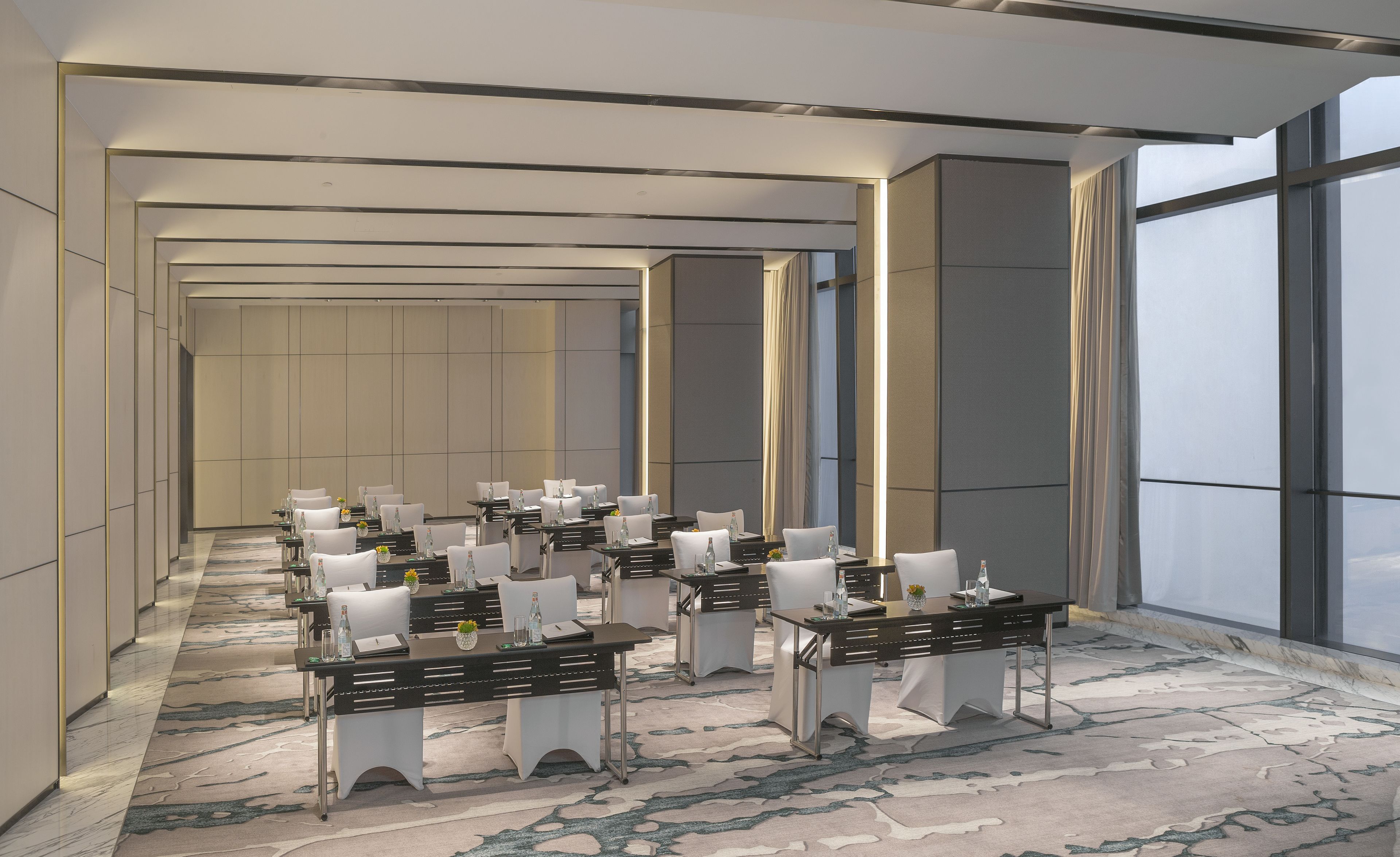 A conference room with multiple tables and chairs, large windows, and a patterned carpet.