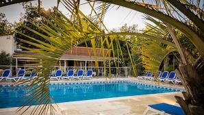 A swimming pool with blue lounge chairs and a tiled deck.
